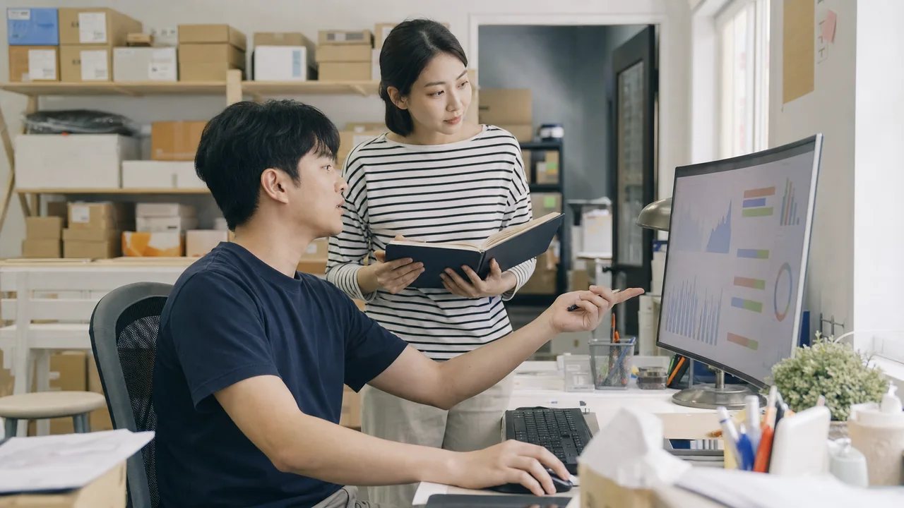 온라인 판매 현황과 재고 데이터를 함께 검토하는 두 명의 운영자